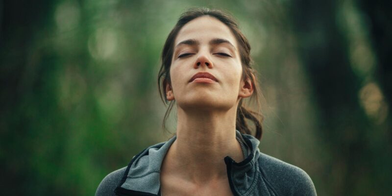 Woman outside practicing mindful breathing exercises as she unites with nature.