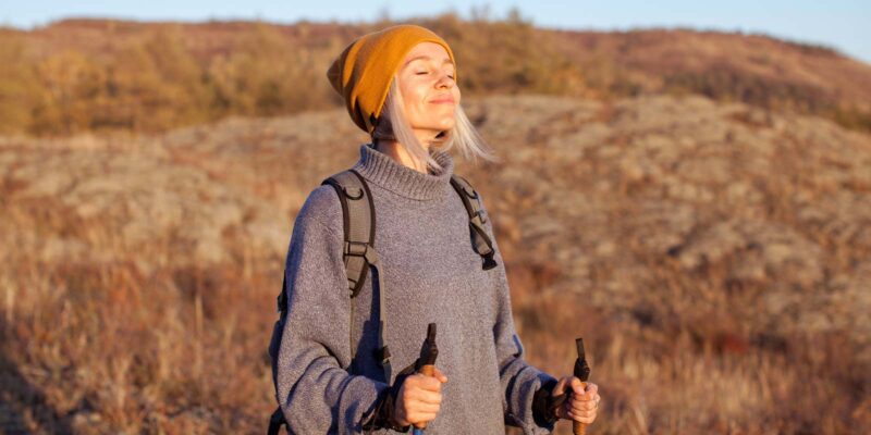 Peaceful woman taking a mindful walk outdoors in a hilly region during fall.